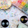 A collection of frosted golden foil acrylic beads and small floral elements scattered on a white surface.