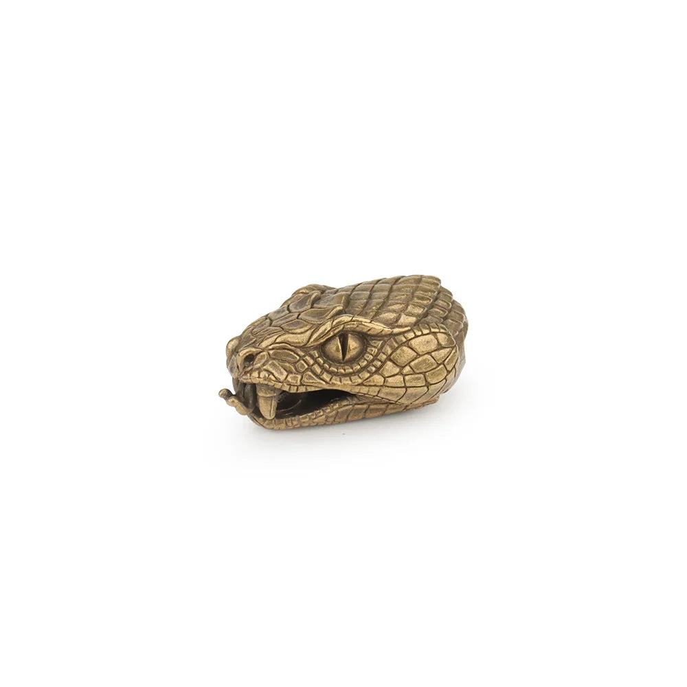 A brass snake head charm used as a paracord lanyard bead.