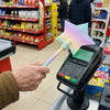 A hand holds a 3D printed magic wand with a star shape towards a payment terminal.