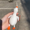 A white and orange jumbo squishy duck stress ball is held in a hand, showing its size with a measurement line.