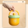 A hand is holding a yellow insulated stainless steel breakfast cup with a green lid.