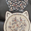 A collection of colorful wooden cat jigsaw puzzle pieces scattered on a dark surface.