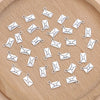 A collection of silver vintage envelope charms for jewelry making arranged on a wooden surface.