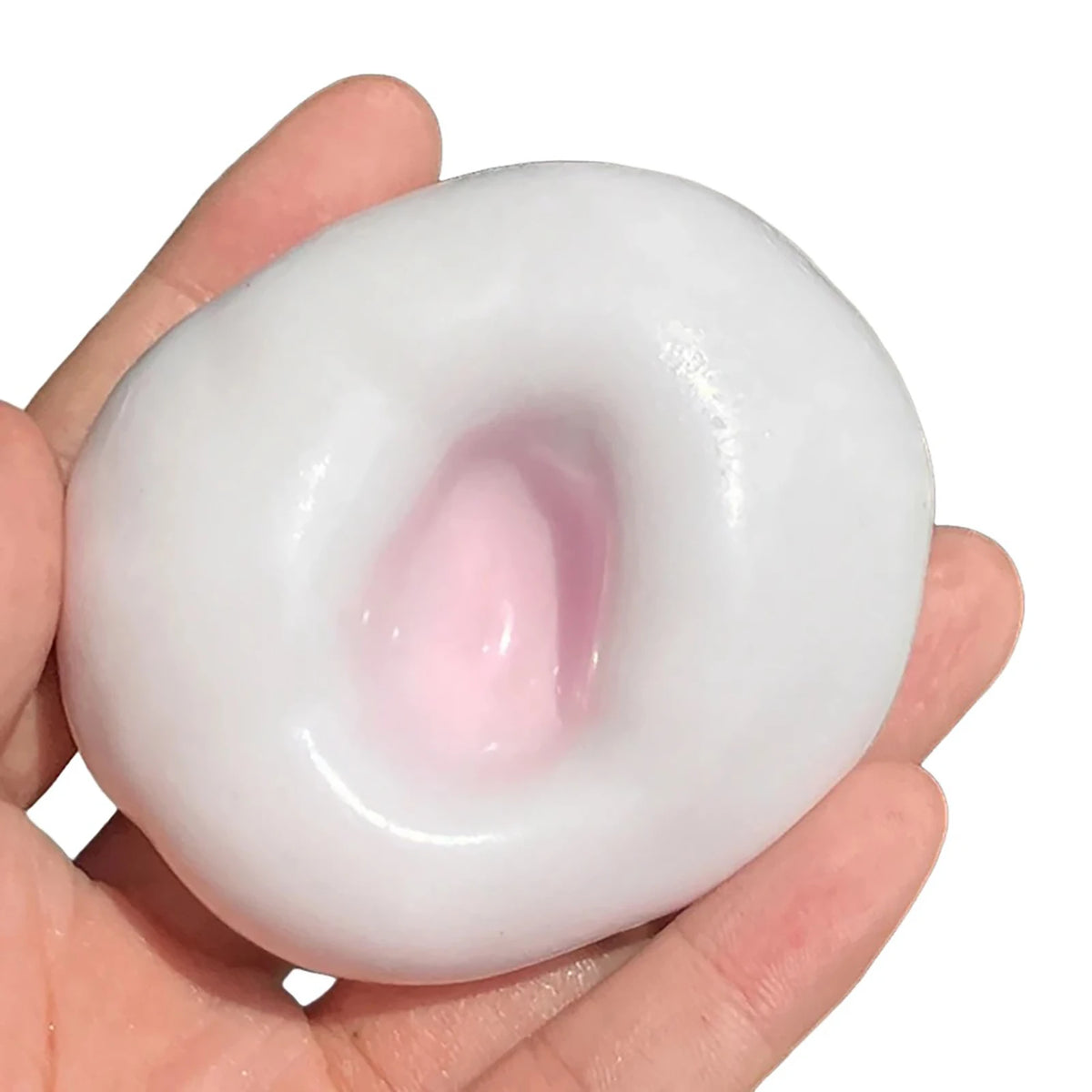 A hand holds a white, squishy stress ball with a pink center, used as a sensory fidget toy.