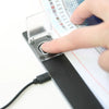 A hand is pressing a clear plastic switch protector cover onto a black light pad device.