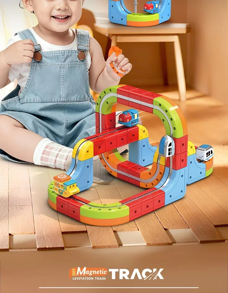 A child is playing with a colorful magnetic train track set on a wooden floor.