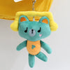 A teal plush pendant doll of a bear with yellow ears and an orange belly hanging from a silver chain.