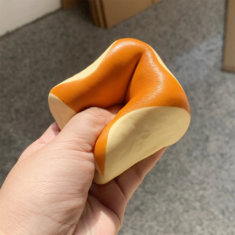 Une main tient un pain décoratif orange et crème, doux au toucher, jouet.