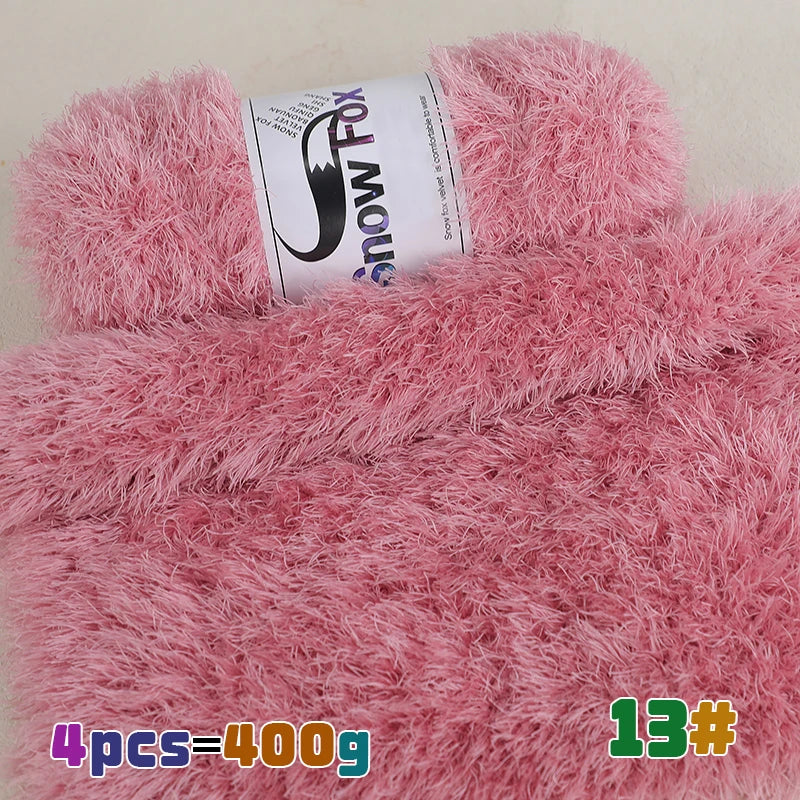 A close-up of pink fluffy faux fur yarn with a label showing the brand Snow Fox and quantity information.