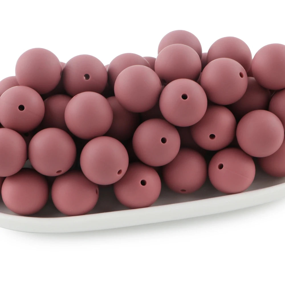 A pile of round, matte pink silicone beads for jewelry making and DIY crafts.