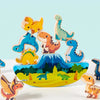 A set of wooden dinosaur stacking blocks in various colors and sizes arranged on a light blue background.
