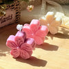 Pink silicone flower molds for soap, candle, and craft making displayed on a wooden surface.