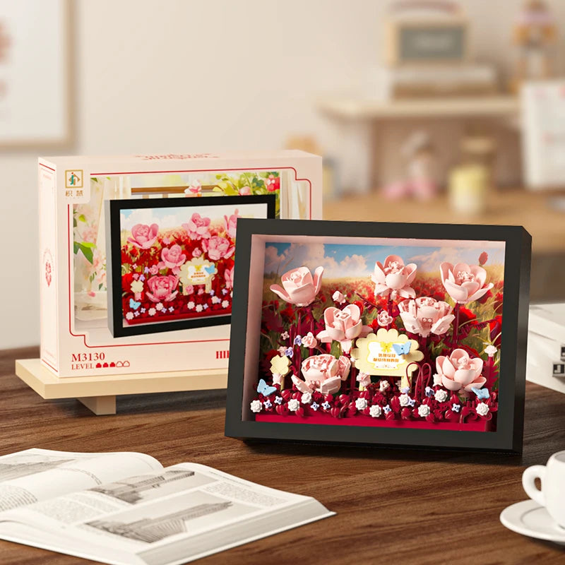 A framed display board showing a vibrant arrangement of pink and red flowers made from 3D building blocks.