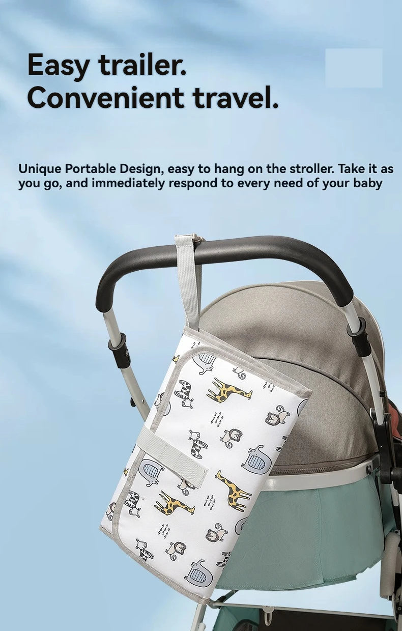 A portable waterproof baby changing mat with a carry handle is shown being used on a stroller.