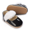 Black patent moccasin shoes for a baby girl with white faux fur trim and bow