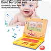 A baby is looking at an orange toddler learning laptop toy with a music feature and lights.