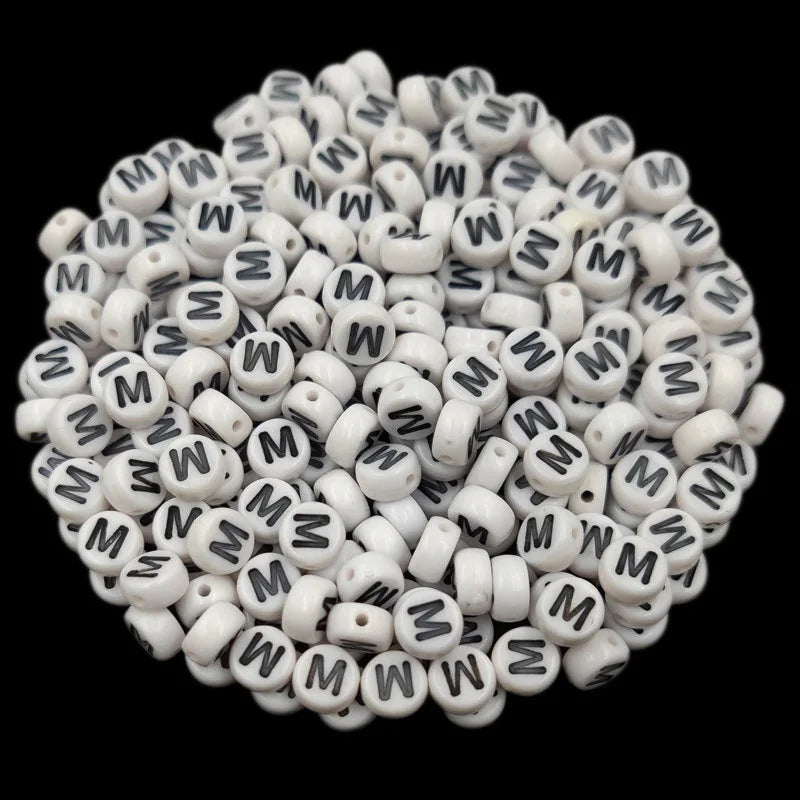 A pile of small white acrylic alphabet letter beads for jewelry making