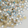 A close-up view of clear and iridescent glass crystal flatback rhinestones in various sizes and gold-toned accents.