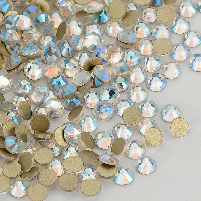 A close-up view of clear and iridescent glass crystal flatback rhinestones in various sizes and gold-toned accents.