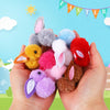 Une main tient un assortiment de lapins en peluche moelleux et d'œufs de Pâques de diverses couleurs comme rose, violet, jaun