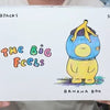 A white card featuring a colorful drawing of a yellow banana plush character with the text The Big Feels and Banana Boo.