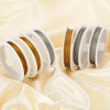 Rolls of stainless steel beading wire in gold and silver colors displayed on silk fabric.