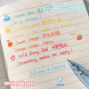 A writing display showing colorful fruit-scented gel pens with labels like Coconut Blue, Candied Lemon, Sweet Orange, and Wil