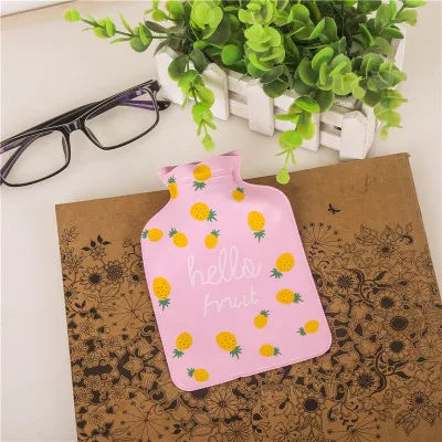 Pink portable hot water bottle with a fruit pattern resting on brown kraft paper.