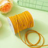 A roll of bright yellow braided ribbon for crafting and gift wrapping lies on a light green surface.