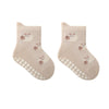 A pair of light beige knitted socks featuring a cute cartoon bear design and non-slip grips on the sole.