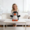 A woman is smiling while sitting on a white sofa with a penguin mini building block toy on a white table.