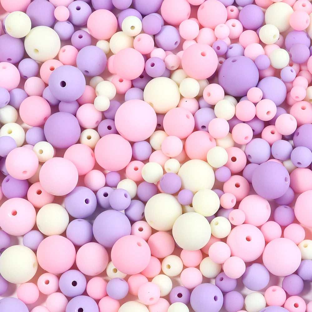 A close-up view of numerous matte acrylic beads in various shades of pink, purple, and white.