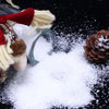 A glass jar filled with white artificial snow powder next to a knitted reindeer decoration on a black background.