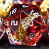 A close-up of a red resin die with golden elven numbers, surrounded by other dice.