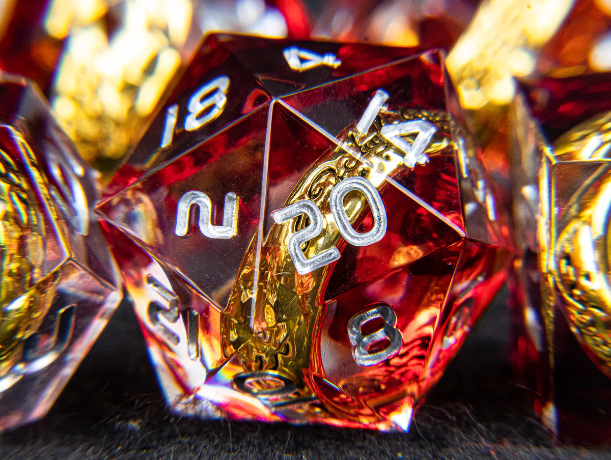 A close-up of a red resin die with golden elven numbers, surrounded by other dice.