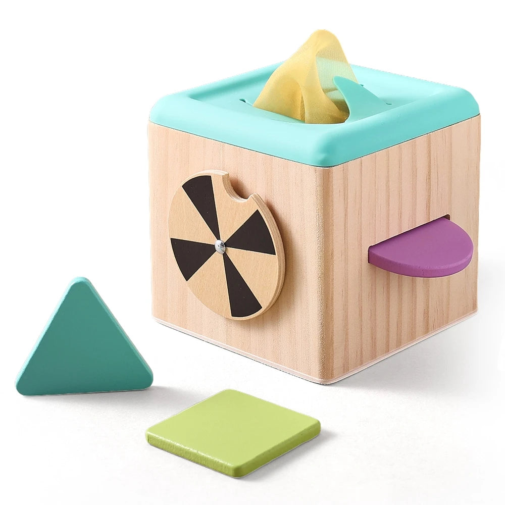 A wooden tissue box with a light blue lid and a pink-purple cutout, alongside green triangular blocks.