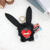 A black fuzzy monster plush toy with large ears and a red mouth, displayed on a white surface.