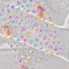 Glittery stickers featuring gold shells and starfish in various pastel colors scattered on white fabric.