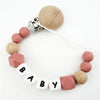 A necklace made of silicone teething beads and a wooden bead, featuring a clip for a pacifier.
