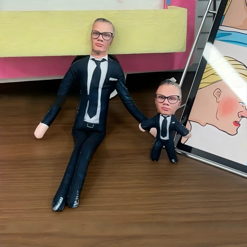 A male and female stuffed doll dressed in suits standing on a wooden floor.