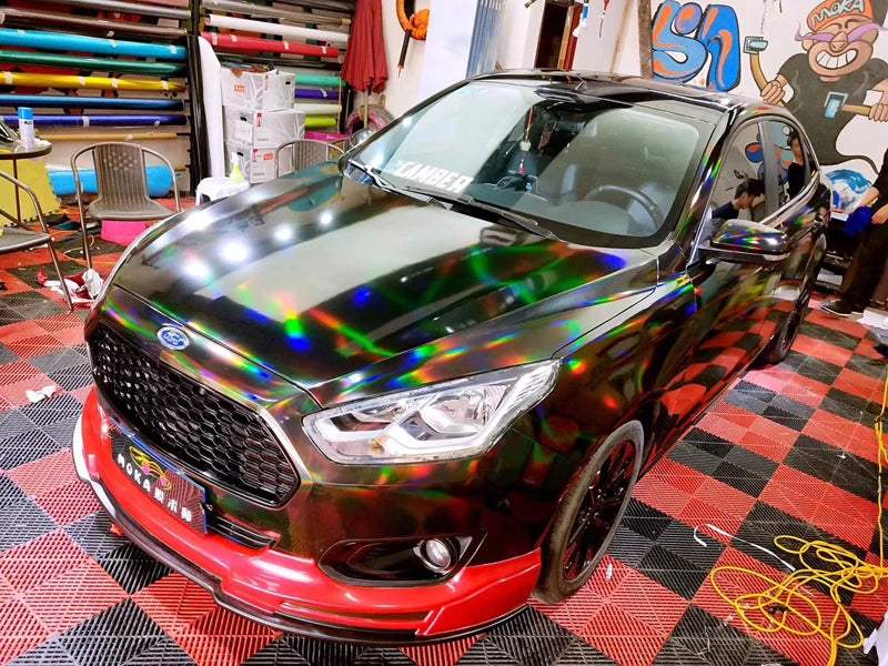 A black Ford Fusion sedan with a holographic chrome vinyl wrap finish parked on a red and black checkered floor.