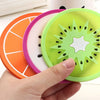 A hand holds a set of colorful fruit pattern PVC coasters, including orange and lime green designs.