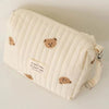 A cream quilted baby diaper caddy organizer with small bear-themed patches and attached stroller straps.
