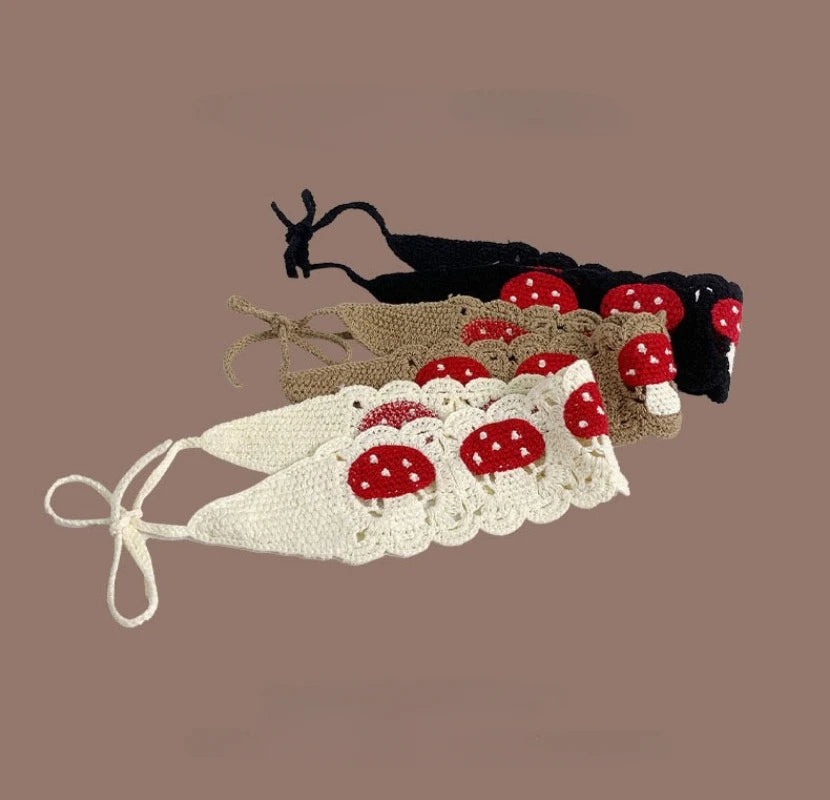 A handmade strawberry crochet headband featuring red and white fabric flowers on a beige background.