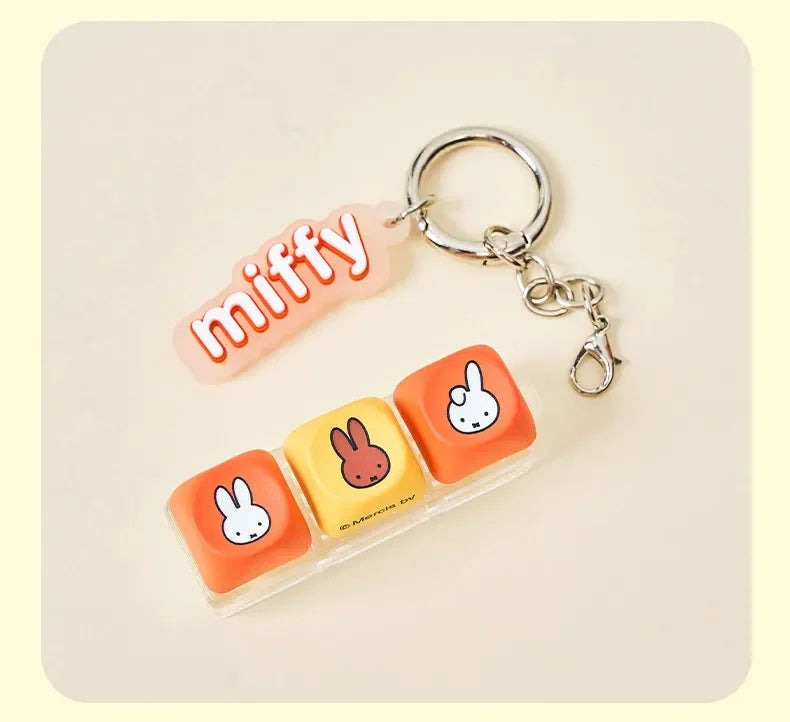 A pink Miffy keycap pendant attached to a silver keyring, displayed on a light background.
