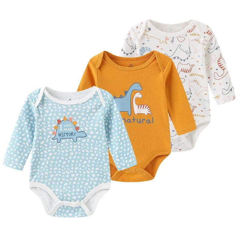 A set of three cotton baby bodysuits with long sleeves in orange, light blue, and white patterns.