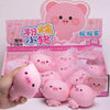 A box of 12 pink pig squishy stress relief toys is shown with a hand holding several of the pink plastic pigs.
