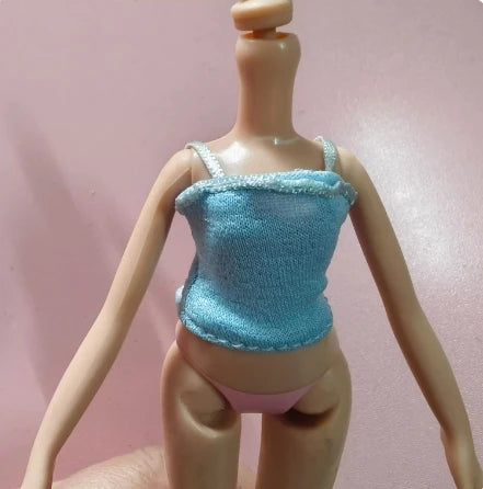 A fashion doll in a light blue top and pink panties is displayed against a pink background.