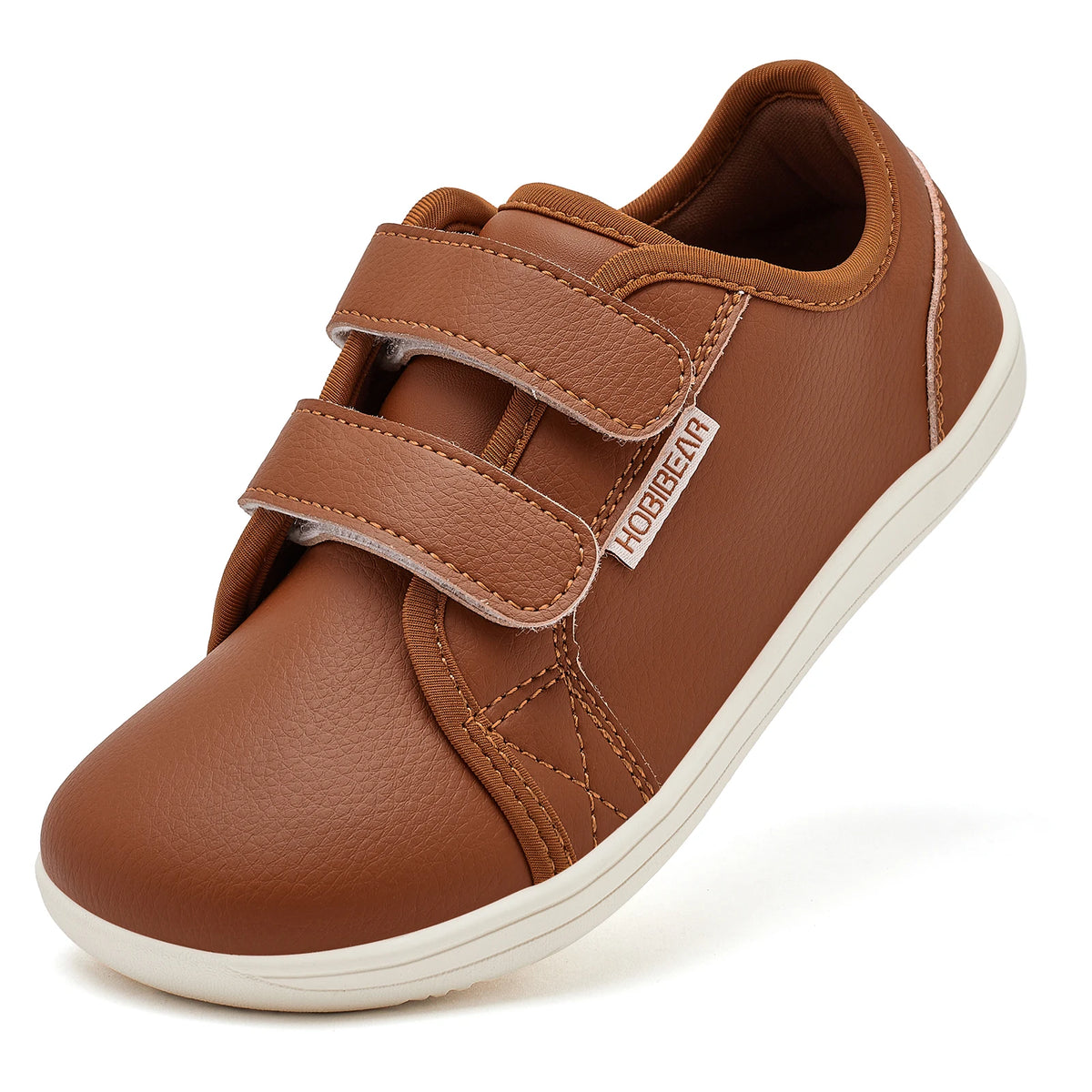 A brown kids barefoot sneaker with double hook-and-loop straps shown from the side.