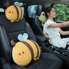 Two yellow plush bee lumbar support pillows with brown stripes and a green plush animal sitting in the back seat of a car.